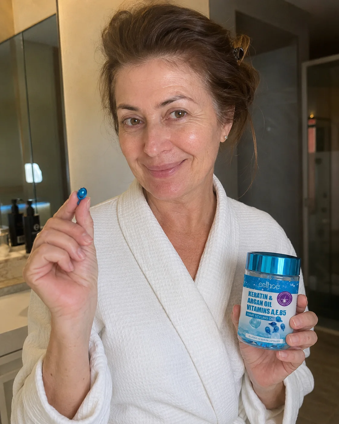 Woman in a robe holding a serum capsule and the Hair Repair Serum bottle