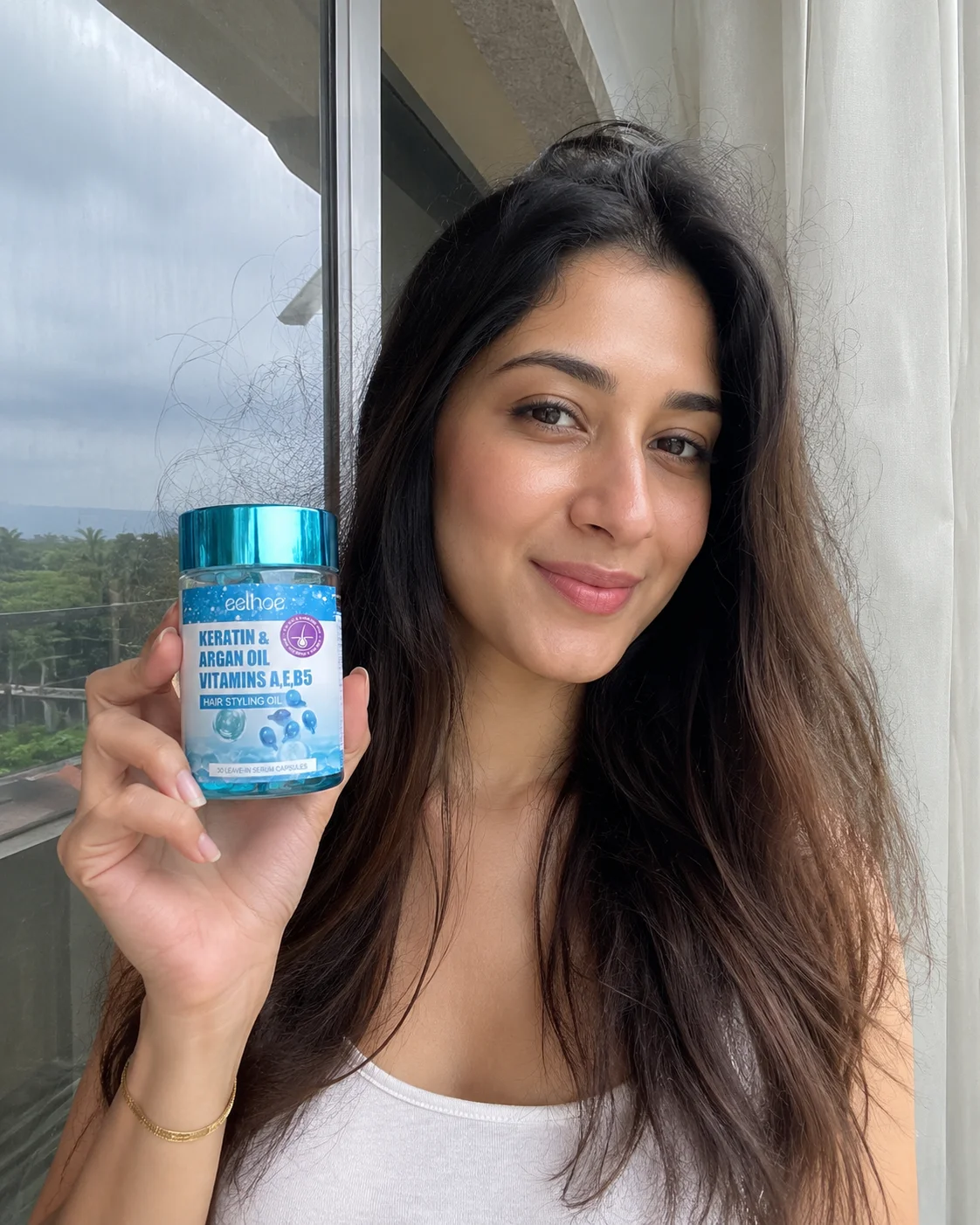 Woman holding the Hair Repair Serum bottle near a window