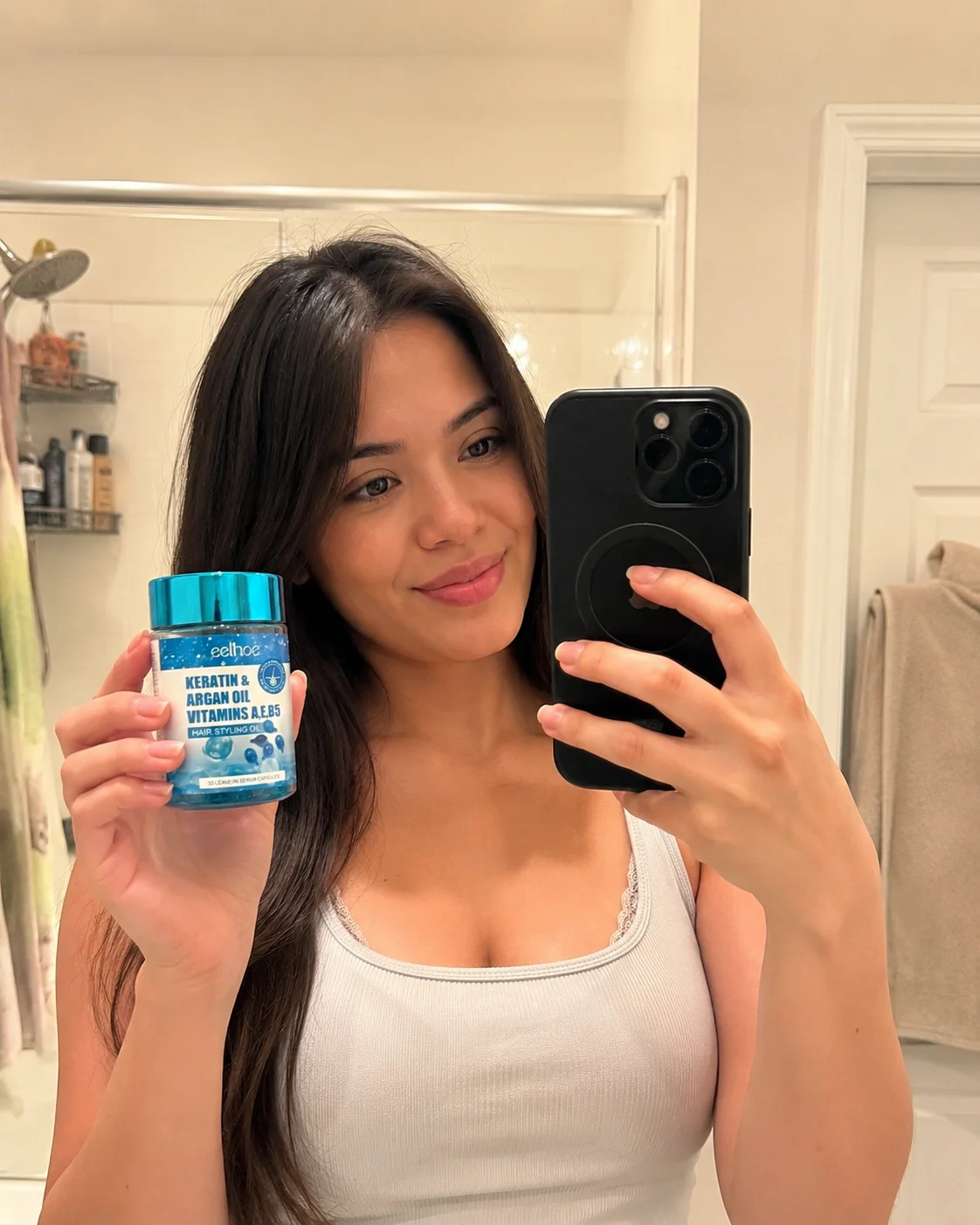 Mirror selfie holding the Hair Repair Serum bottle